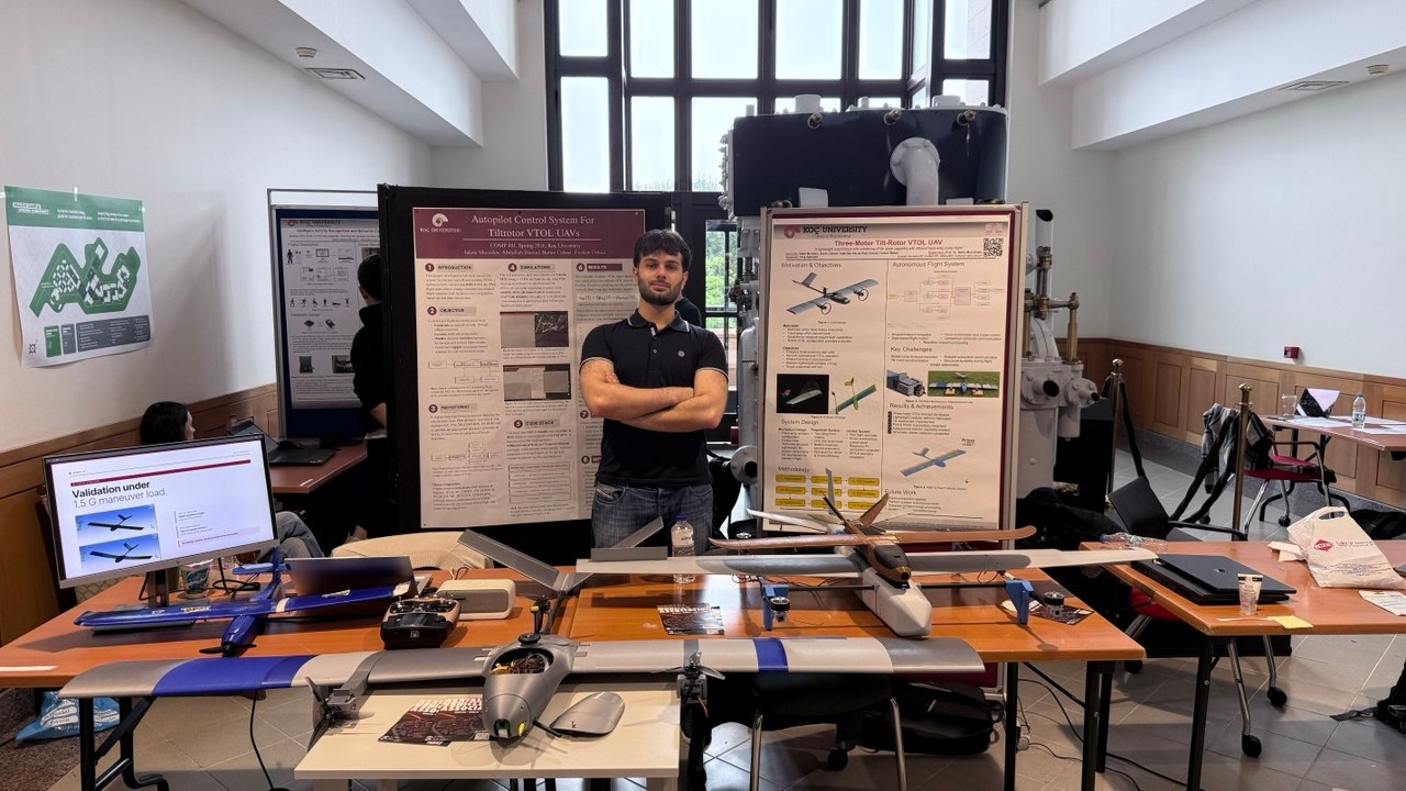 Islam standing with UAV prototypes and engineering posters at a project exhibition